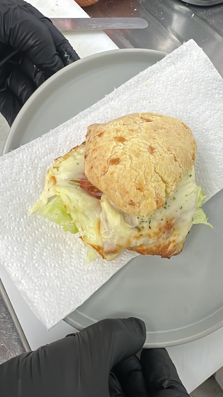 A small filled Brazilian cheese-bread roll with cheese and lettuce, served on a napkin